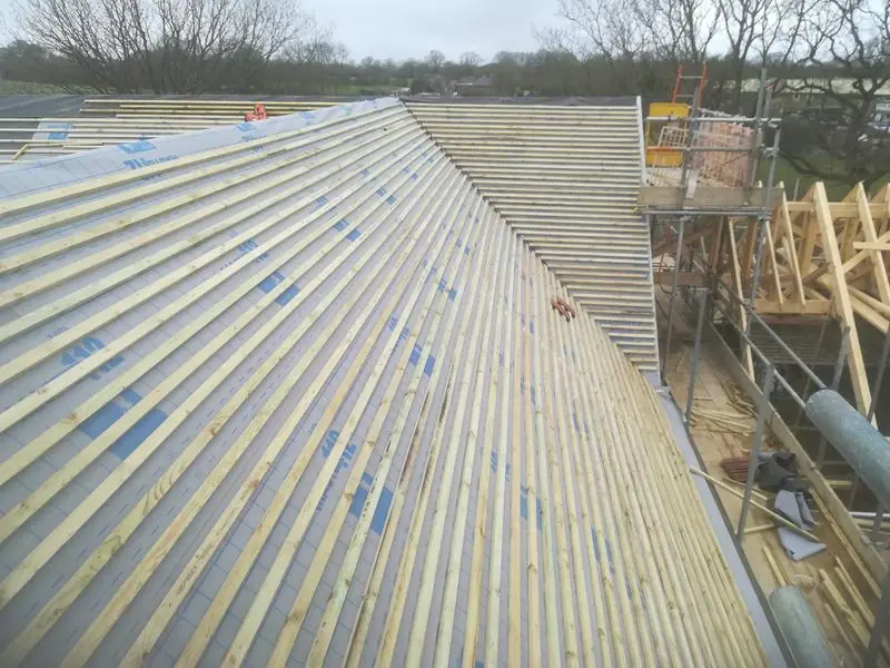 New timber battens fixed across a long pitched roof over breathable membrane, ready for tiles