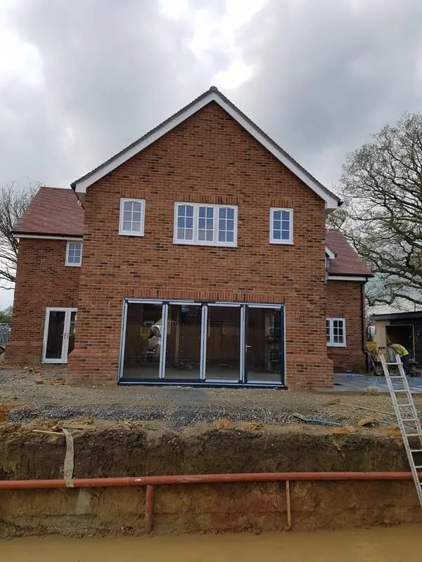 Back of a new-build brick house with a tiled roof and gable, under a cloudy sky