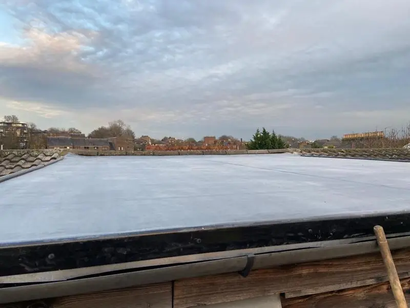 Newly covered flat roof with a neat trimmed edge, looking out over rooftops at dusk